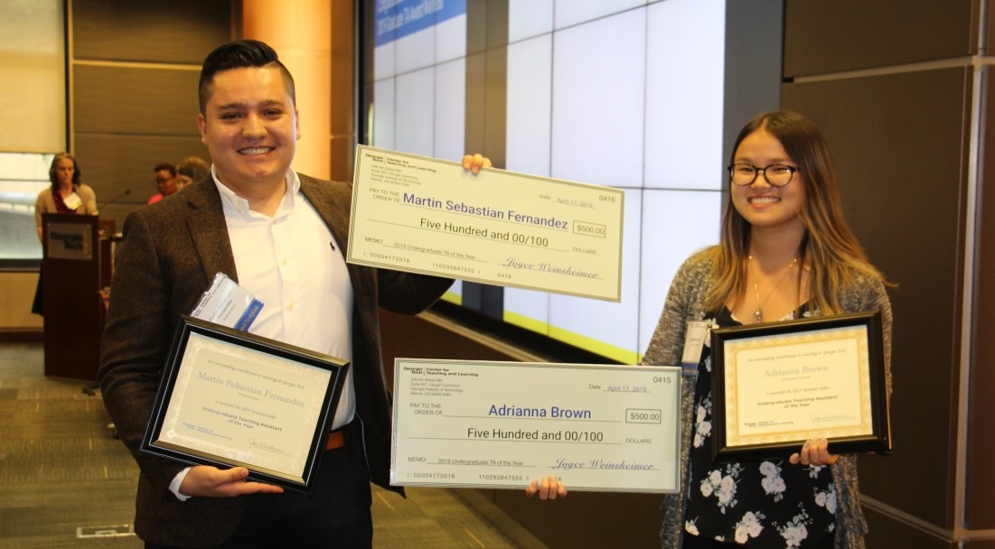 Two people holding award certificates